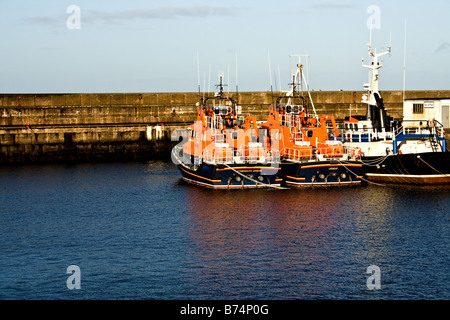 Due di salvataggio arancione rimorchiatori a Buckie porto dietro un muro di cemento sull'acqua del Moray Firth in Scozia Foto Stock