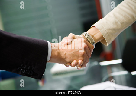 L uomo e la donna si stringono la mano in ufficio durante la riunione. Vista dettagliata del maschio e femmina mani, con escursioni in background. Foto Stock