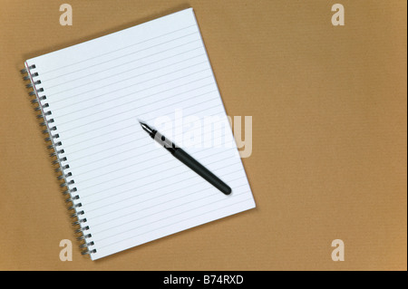 Notebook a spirale e penna stilografica su un marrone sfondo della carta Foto Stock