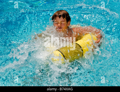 Smorfie di 10 anno vecchio ragazzo cade in una piscina a Laguna Niguel ca nota galleggiante giallo modello di rilascio Foto Stock