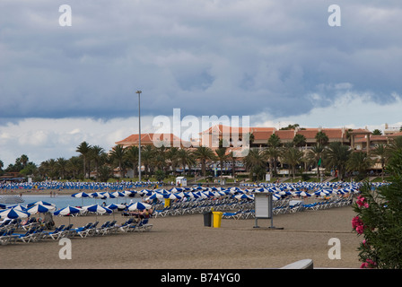 Una scena di spiaggia presso la località di villeggiatura balneare di Playa de las Americas, Tenerife, Spagna. Foto Stock
