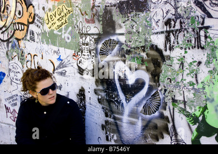 Una donna in nero accanto a un muro con graffiti. Foto Stock