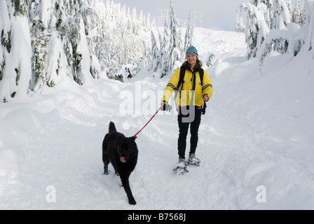 Donna con le racchette da neve con il cane, Cypress Mountain Ski Resort, West Vancouver, BC, Canada Foto Stock