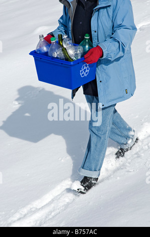 Casalinga tenendo fuori il blue box pieno di bottiglie e lattine per il riciclaggio Foto Stock