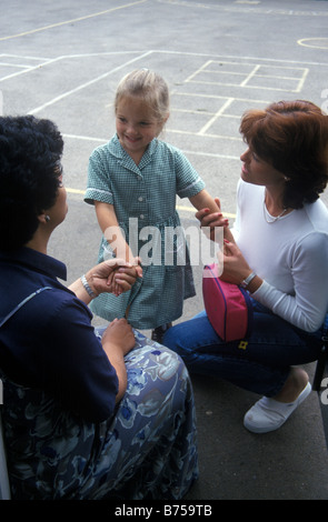 Madre di lasciare la figlia con il maestro per il suo primo giorno di scuola primaria Foto Stock