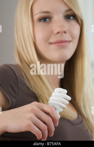 Close-up di giovane donna azienda compatta lampadina fluorescente, Brandon, Manitoba, Canada Foto Stock