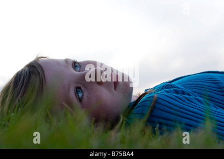 Headshot, otto anni che ragazza distesa in erba guardando verso l'alto, Winnipeg, Canada Foto Stock