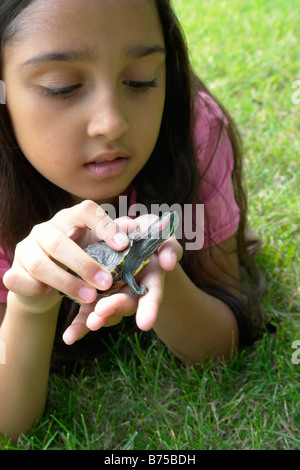 8 anno vecchia ragazza giacente in erba con la tartaruga, Winnipeg, Canada Foto Stock