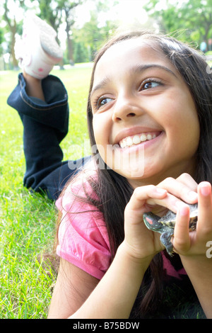 Sorridente otto anni che ragazza distesa in erba con la tartaruga, Winnipeg, Canada Foto Stock