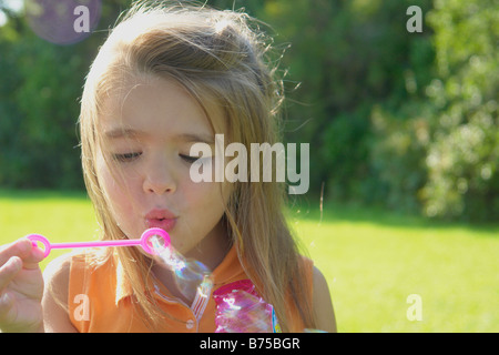 6 anno vecchia ragazza soffiare bolle nel parco, Winnipeg, Canada Foto Stock