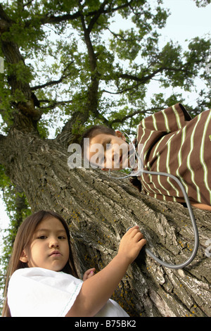 Angelo Basso, di cinque e sette anni di sorella e fratello con stethescope su albero, Winnipeg, Canada Foto Stock