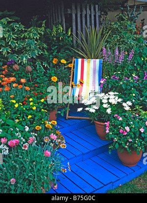 Tela a strisce sedia Circondato da colorati contenitori piantate nel blu dipinto di fasi Foto Stock