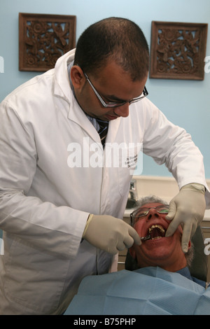 Un dentista di eseguire un intervento di chirurgia dentale su un paziente maschio utilizzando l'ipnosi e non utilizzando anestetico Foto Stock