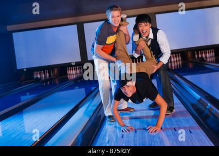 Ritratto di tre amici divertendosi in una pista da bowling Foto Stock