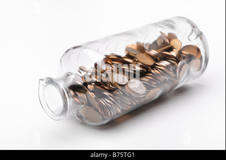 Bottiglia di vetro piena di monete su sfondo bianco Foto Stock