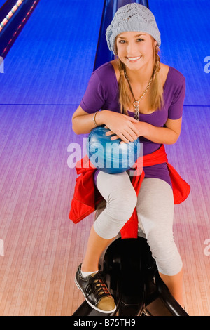 Ritratto di una ragazza adolescente tenendo una palla da bowling e sorridente Foto Stock