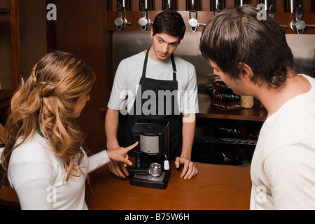 Coffee shop proprietario che mostra una macchina per il caffè per i clienti Foto Stock