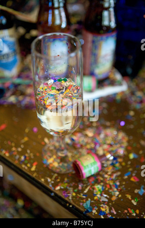 Cenone di capodanno con ballo relitto compreso un bicchiere di champagne con i confetti che galleggia sulla superficie del vetro di champagne Foto Stock