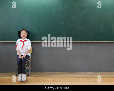 Un ritratto di una scuola cinese ragazza seduta di fronte a una lavagna. Foto Stock