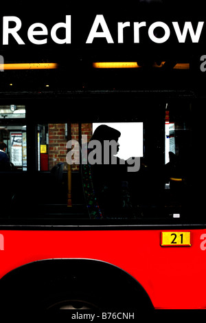 Freccia rossa autobus che mostra la silhouette di una donna seduta su un fuori la stazione Victoria London REGNO UNITO Foto Stock