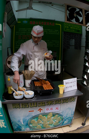 Un giovane uomo si prepara la colazione al primo freddo inverno mattina per passare dai pendolari su una strada laterale Foto Stock