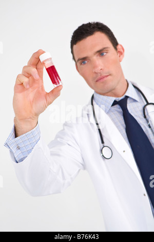 Un medico di sesso maschile di esaminare un campione di sangue per il focus è sulla fiala di sangue Foto Stock