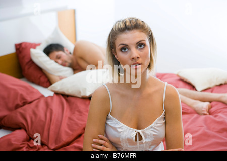 Gelangweilte Frau im Schlafzimmer ihr Mann schlaeft, annoiato donna nella camera da letto del loro uomo dorme Foto Stock