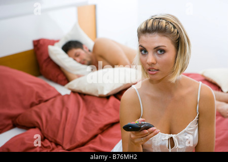 Gelangweilte Frau im Schlafzimmer ihr Mann schlaeft, annoiato donna nella camera da letto del loro uomo dorme Foto Stock