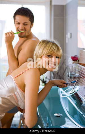 Paar beim Zaehneputzen im Badezimmer, giovane con uno spazzolino da denti in bagno Foto Stock