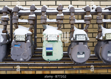 Una fila di contatori del gas riposare al freddo e neve mentre sono in grado di offrire il gas per tenerci caldi. Foto Stock