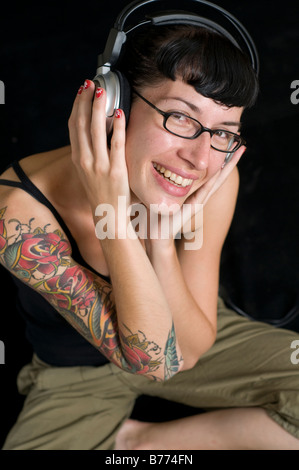 Donna con tattoo ascoltando musica sulle cuffie Foto Stock