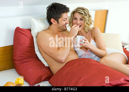 Paar beim gemeinsamen Fruehstueck im Bett, giovane avente insieme per la prima colazione a letto Foto Stock