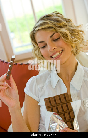 Frau isst Schokolade, giovane donna mangiare grandi barretta di cioccolato Foto Stock