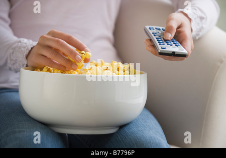 Close up della donna il controllo remoto e una ciotola di pop-corn Foto Stock