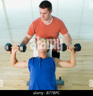 Personal trainer spotting uomo manubri Foto Stock