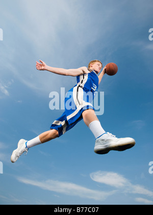 Teenage giocatore di basket mid-air basket Foto Stock