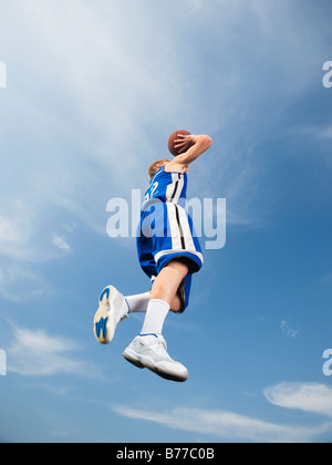 Teenage giocatore di basket a metà riprese aria basket Foto Stock