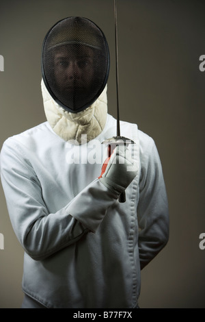 Ritratto di fencer uniforme e maschera holding lamina di scherma Foto Stock