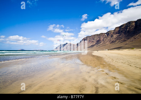 Playa de Famara risco de Famara spiaggia di sabbia di montagna rocce riflessione Lanzarote isole Canarie Spagna Foto Stock