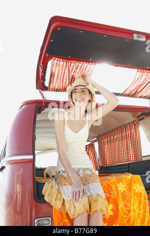 Giovane donna appoggiata contro il retro del furgone Foto Stock