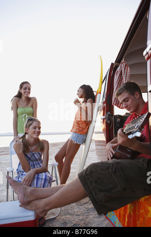 Gli amici di oziare intorno a van sulla spiaggia Foto Stock