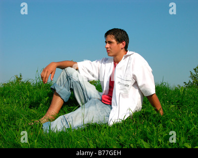 Ragazzo seduto su un prato in estate Foto Stock