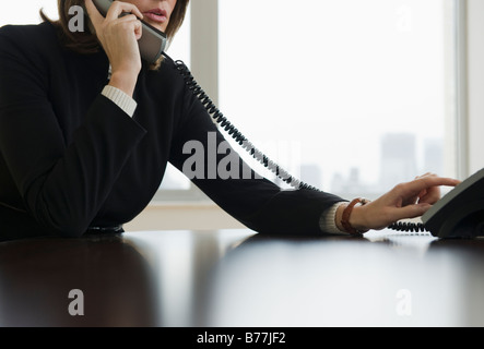 Donna composizione mediante telefono ufficio Foto Stock
