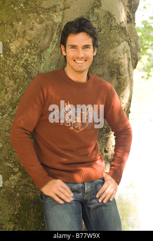 Uomo appoggiato a un albero Foto Stock