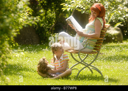 Ragazza e la donna incinta seduti in giardino Foto Stock