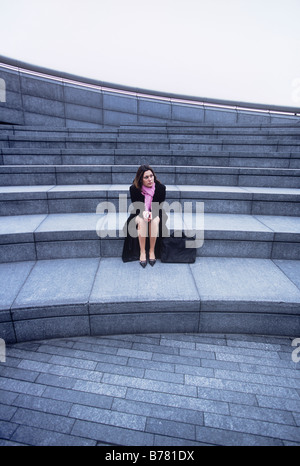 Imprenditrice da sola seduta sui gradini Foto Stock