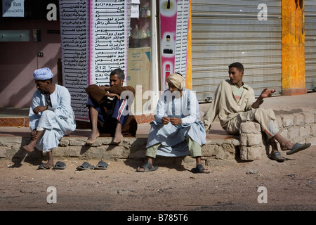 Un gruppo di gente del posto sedersi sul cordolo in Dahab egitto Foto Stock