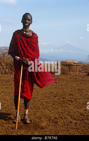 Orizzonte Monte Kilimanjaro di haze capanna o casa di paglia tribù Masai Gioielli uomo Stick pastore MASAI MARA TANZANIA Foto Stock