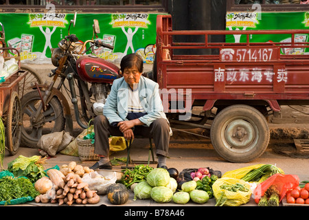 Una donna che vende le verdure in una strada nella città cinese di Pingyao nella provincia di Shanxi. Foto Stock