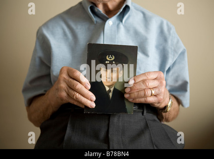 Un anziano veterano trattiene una immagine di se stesso come un ufficiale di marina mercantile durante la Seconda Guerra Mondiale la seconda guerra mondiale Foto Stock